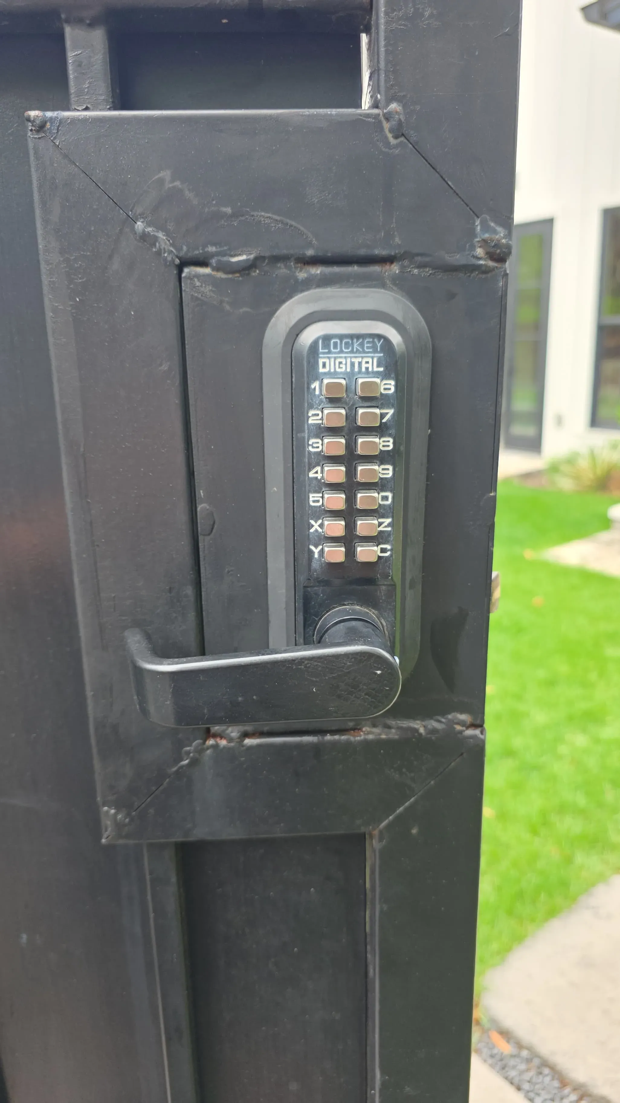 A Lockey digital keypad lock installed on a black commercial security gate