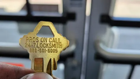 Pros On Call branded brass key displayed at a legitimate commercial locksmith storefront in Austin TX