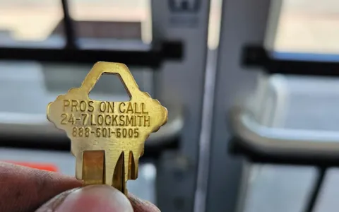 Pros On Call branded brass key displayed at a legitimate commercial locksmith storefront in Austin TX
