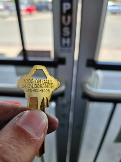 Pros On Call branded brass key displayed at a legitimate commercial locksmith storefront in Austin TX