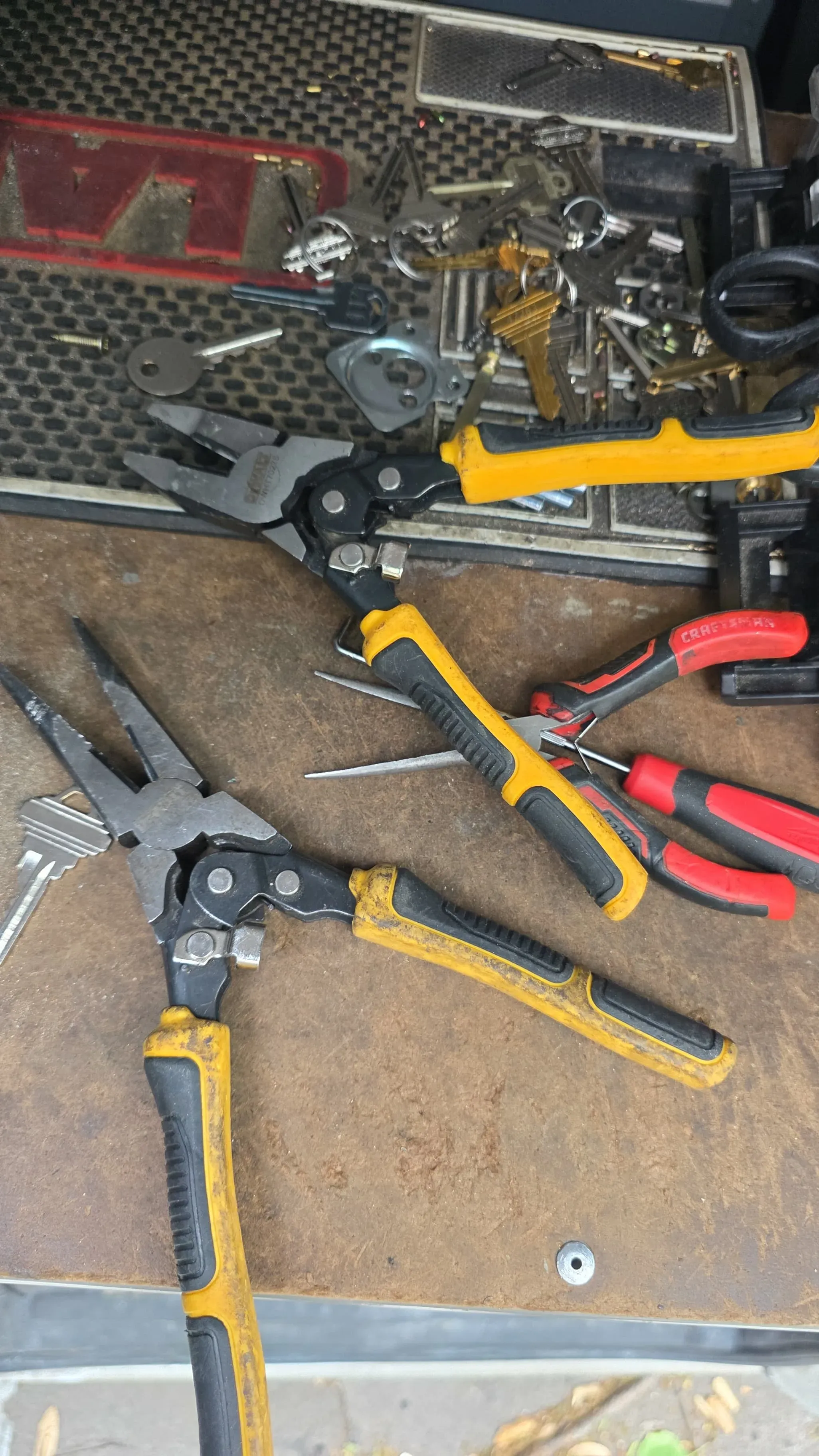 An overhead view of locksmith pliers, picks, and a pile of keys and hardware on a service tray