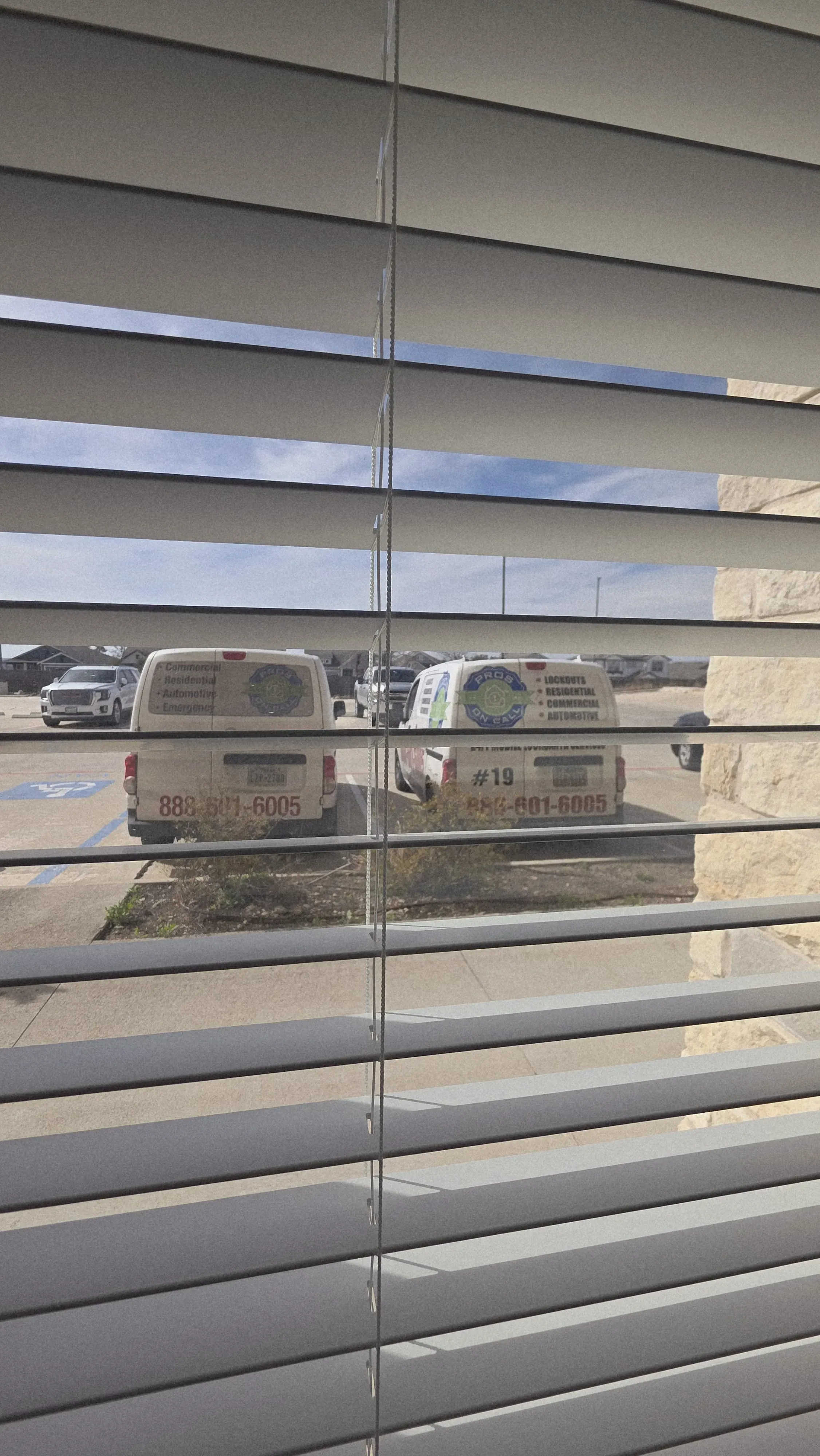 Pros On Call service vans viewed through window blinds at a Texas property