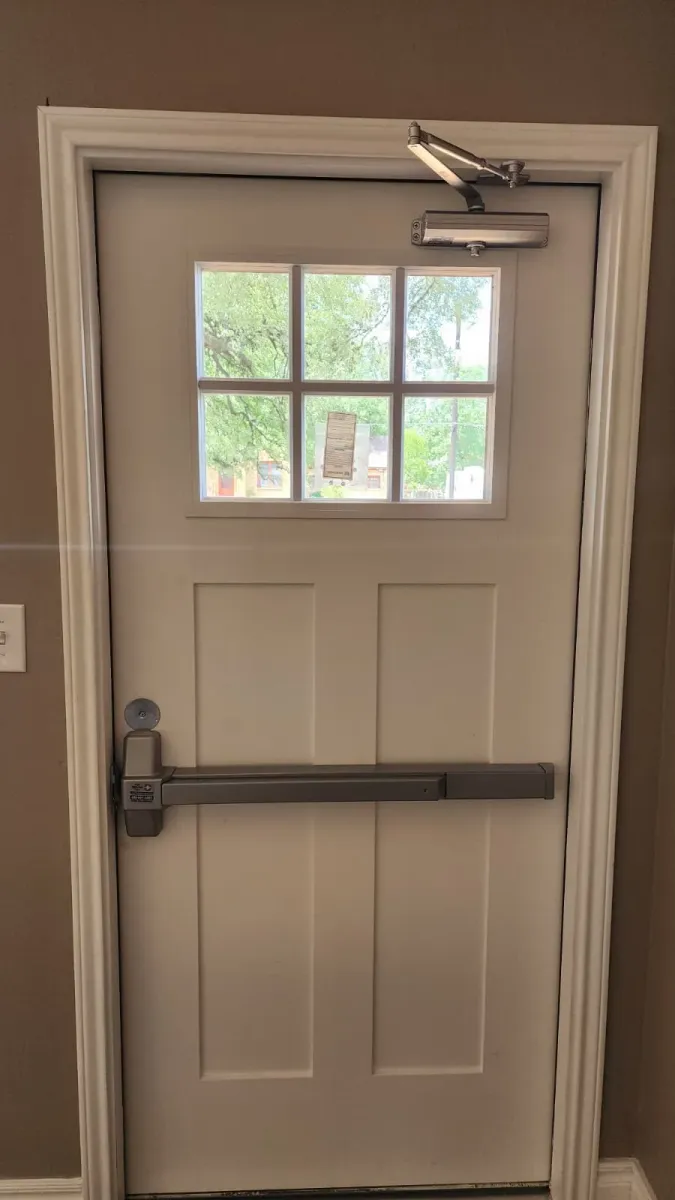 Close-up of commercial panic bar hardware and door closer after installation