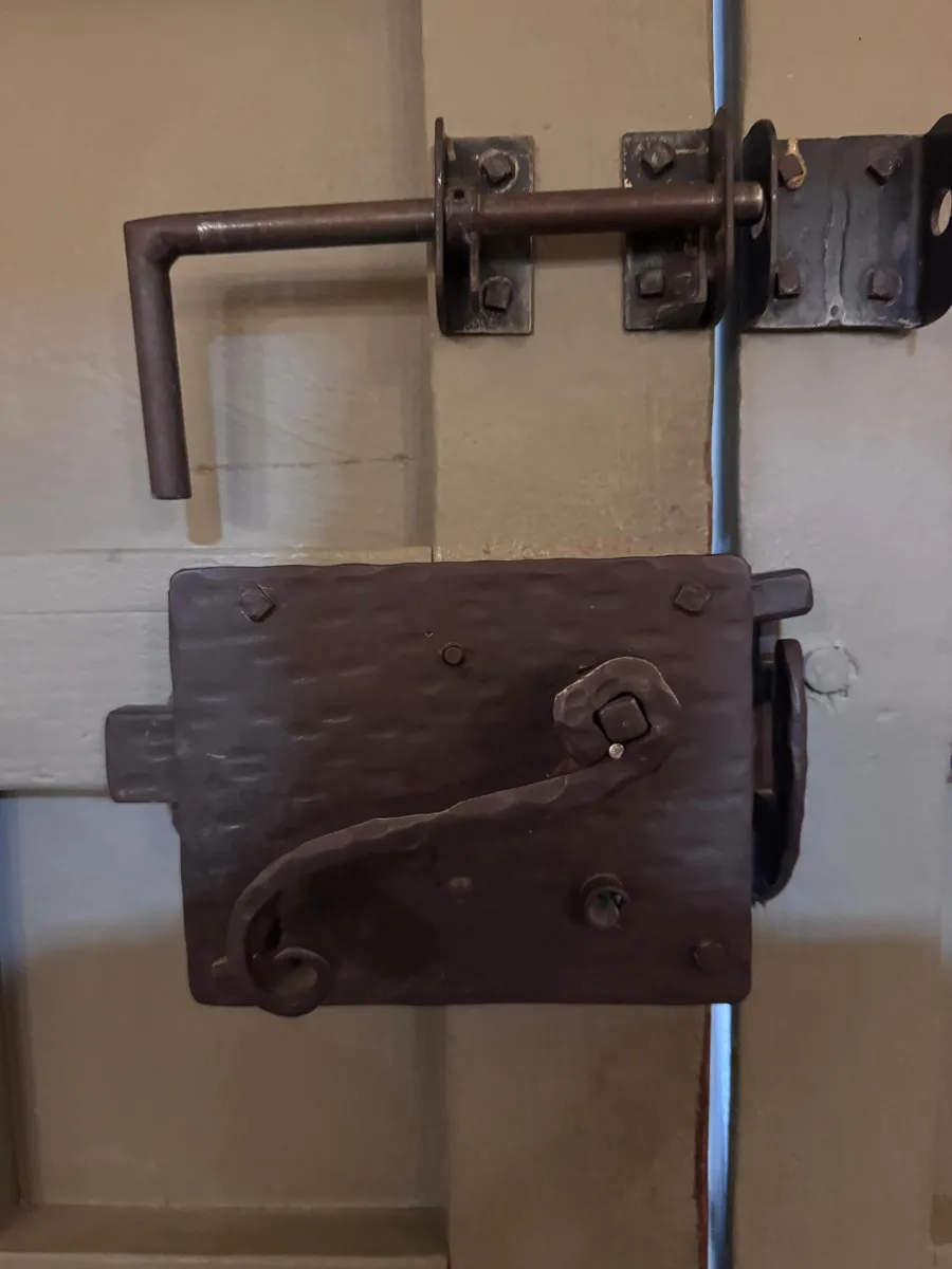 Antique wrought iron latch and bolt hardware on a residential door