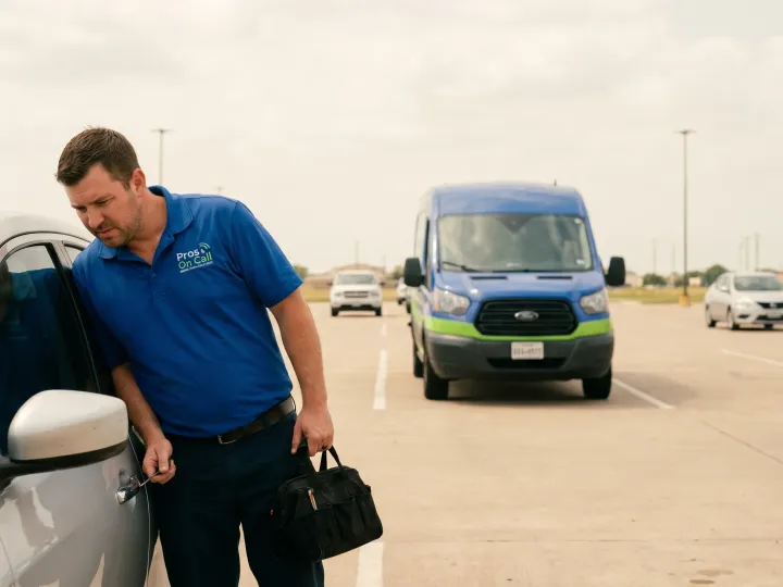Pros On Call technician unlocking a car door in an Austin Texas parking lot, branded cobalt blue and lime-green service van parked behind.