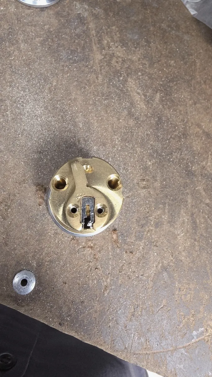 Brass mortise lock cylinder laid out on a workbench for commercial service