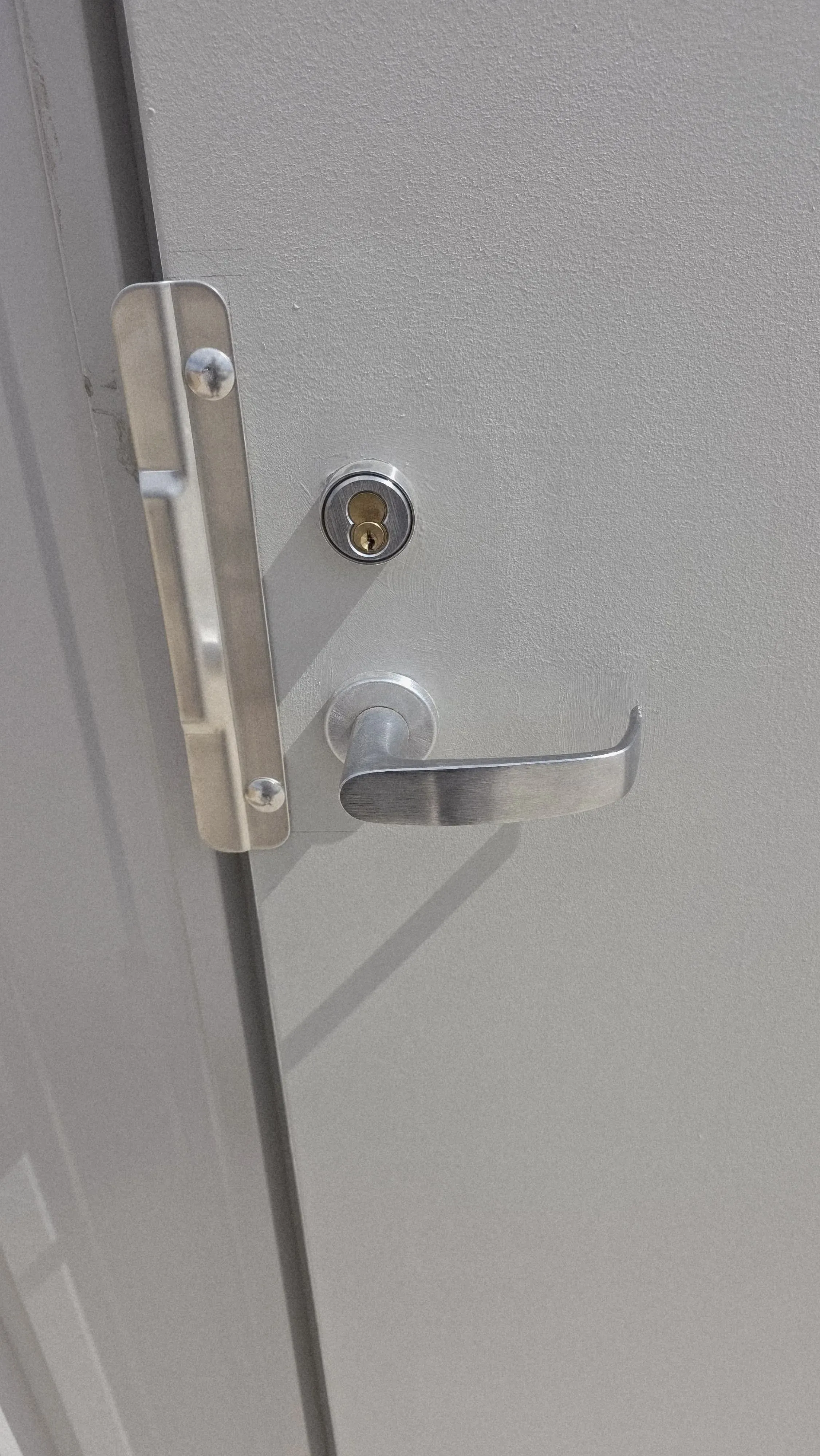 Lever handle and deadbolt hardware installed on a grey door