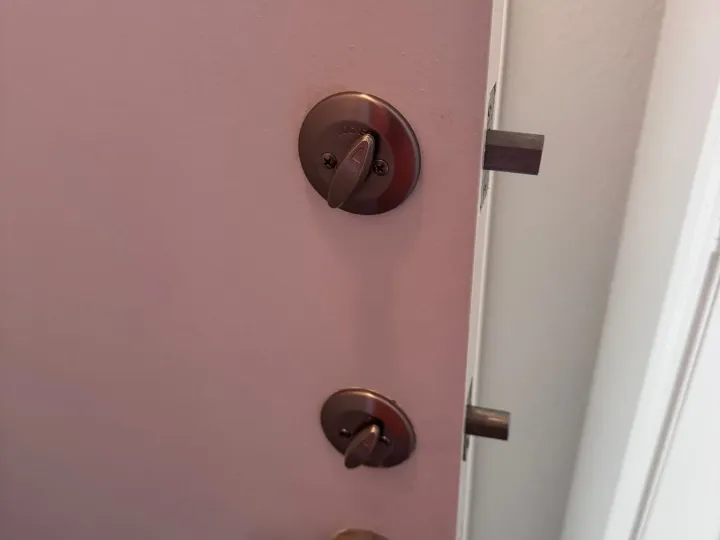 Bronze deadbolt and lever installed on the edge of an Austin apartment door by Pros On Call residential locksmith.