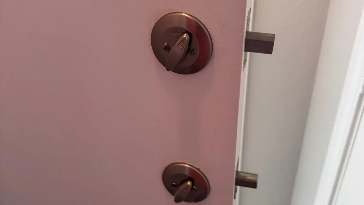 Bronze deadbolt and lever set on an apartment door in Austin TX, a Pros On Call residential security upgrade