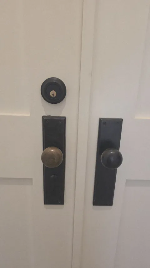 Pros On Call locksmith in progress installing a door knob and deadbolt on a residential door in Austin TX, showing the work behind service costs