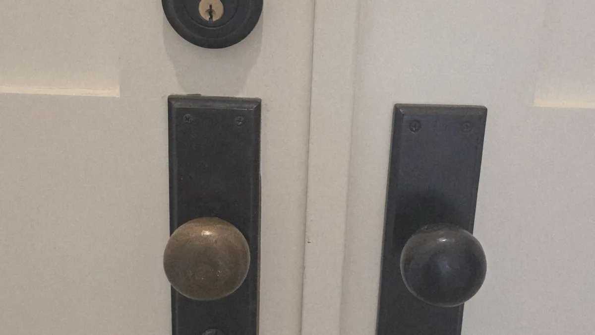 Pros On Call locksmith in progress installing a door knob and deadbolt on a residential door in Austin TX, showing the work behind service costs