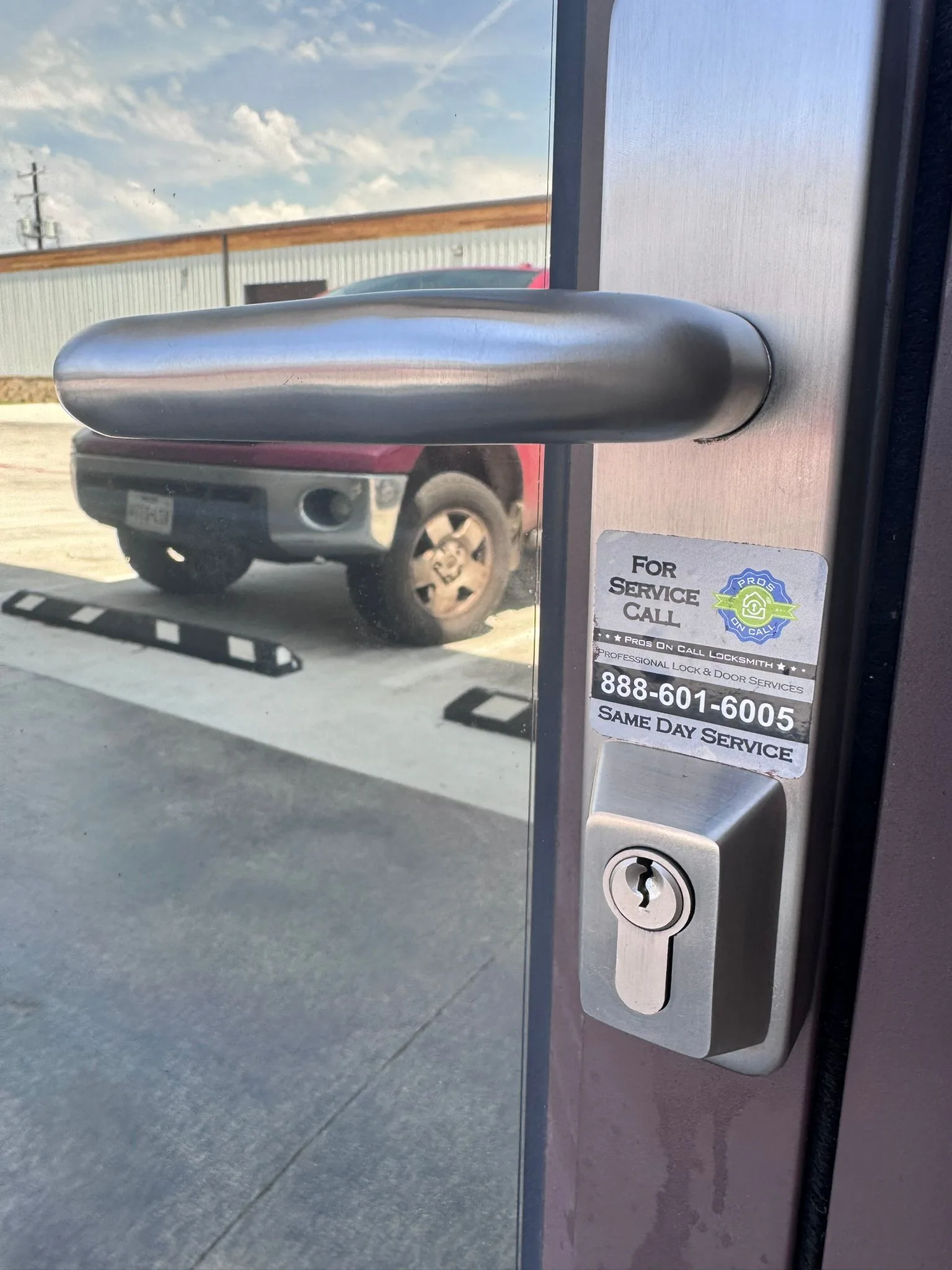 Pros On Call service sticker on a glass door handle with branded truck visible