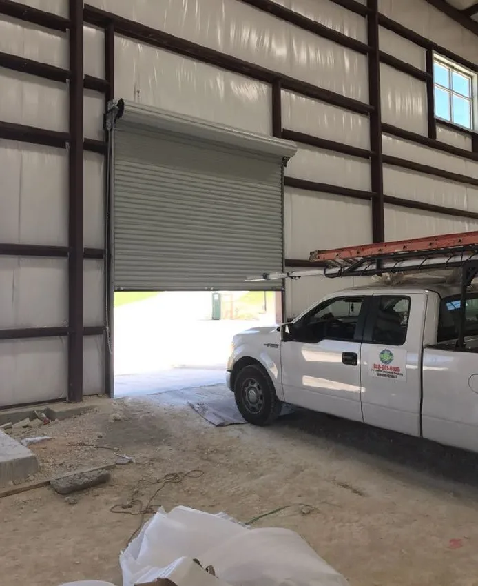 Commercial roll-up door installed inside metal building by Pros On Call, truck visible