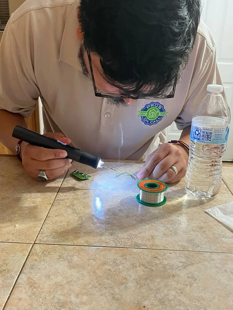 Pros On Call technician in branded polo soldering a key fob circuit board on site